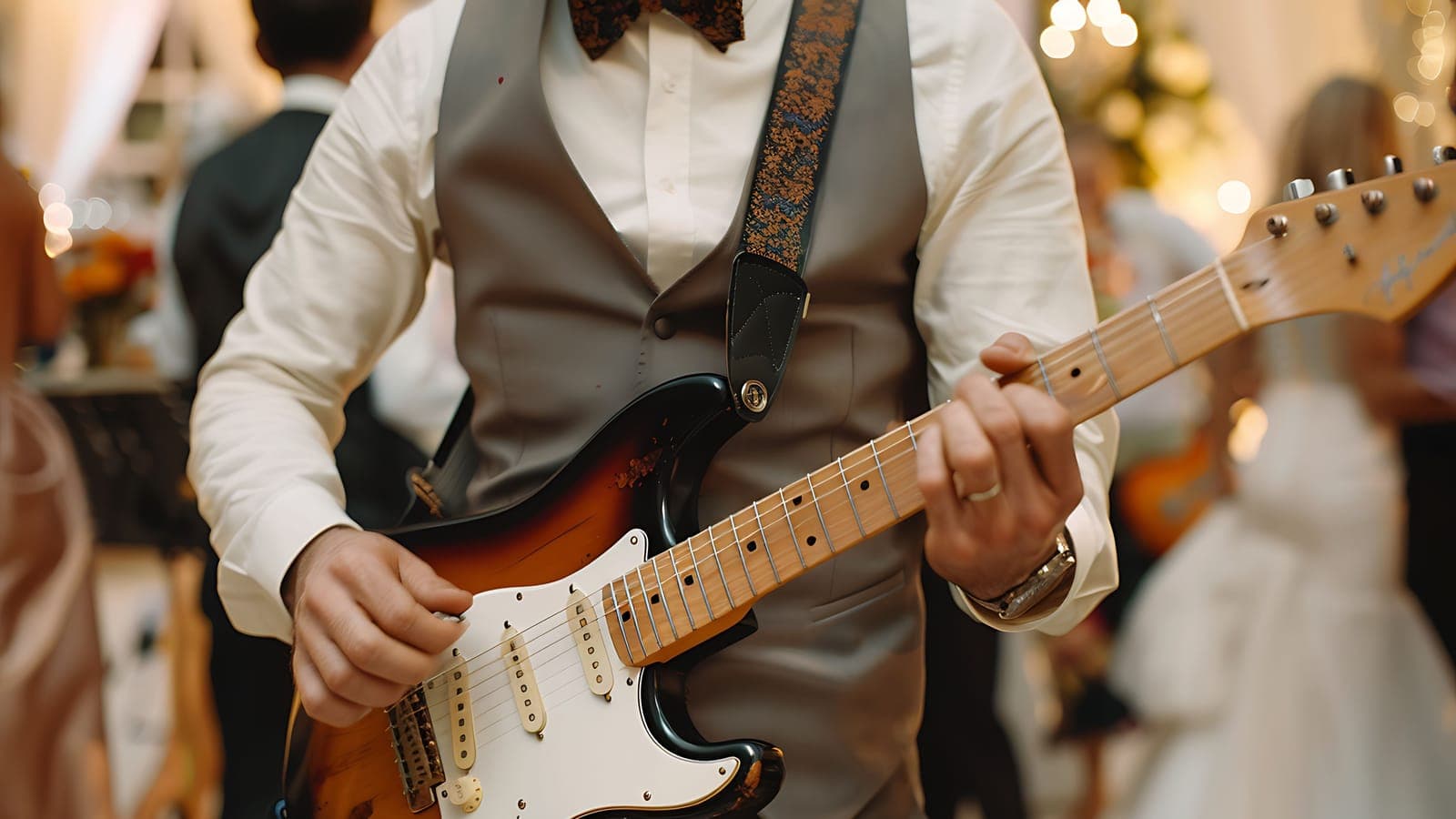 Muzyk zespołu weselnego w kamizelce i muszce gra na gitarze elektrycznej
